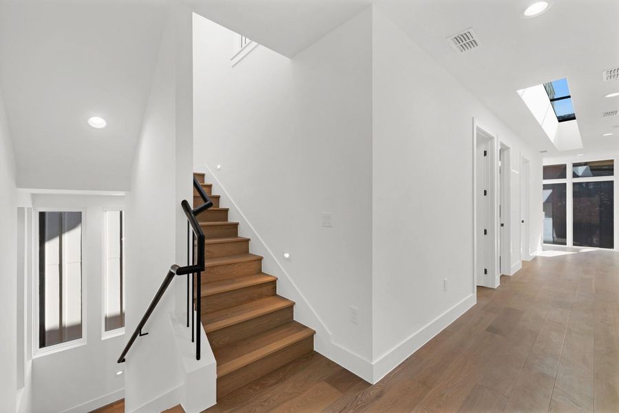 Stairs with recessed lighting, a skylight, and wood finished floors Stairs with recessed lighting, a skylight, and wood finished floors