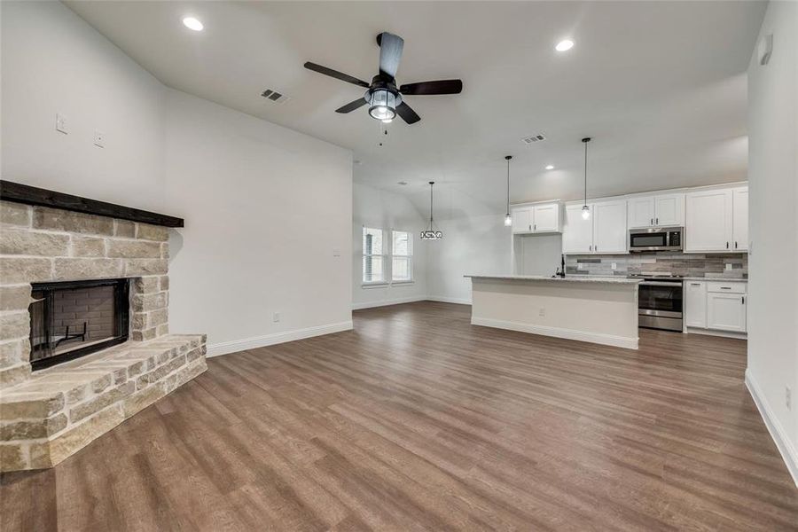 Unfurnished living room with a fireplace, recessed lighting, a ceiling fan, and dark wood-style floors