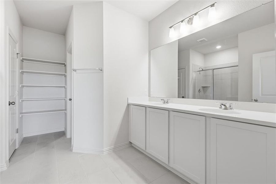 Dual vanity with white cabinetry and countertops, featuring a large wall-mounted mirror and contemporary lighting fixture