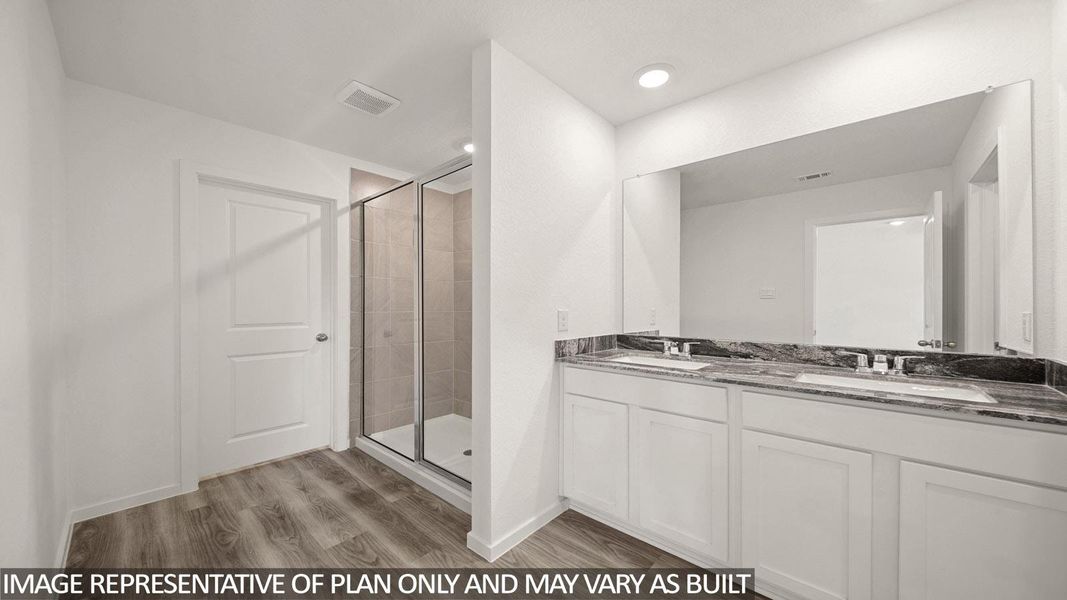 Bathroom featuring a double vanity with stone countertop, dual undermount sinks, and a frameless mirror