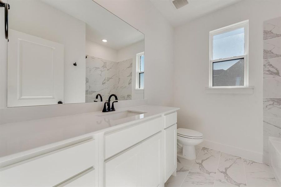 Bathroom with light marble finish flooring, vanity, plenty of natural light, recessed lighting, and a combined bath / shower with marble appearance Bathroom with light marble finish flooring, vanity, plenty of natural light, recessed lighting, and a combined bath / shower with marble appearance