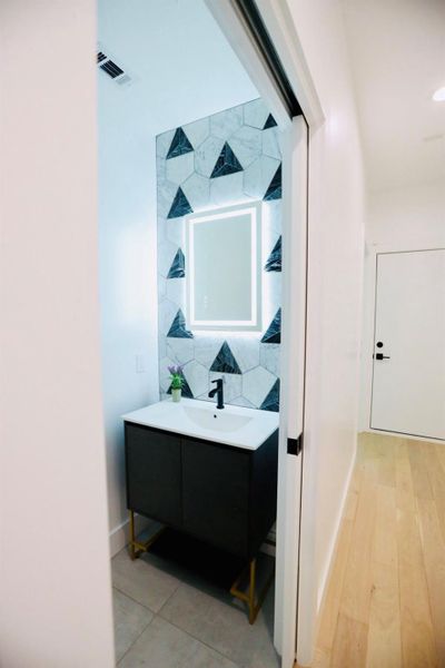 Half bathroom featuring vanity and tasteful backsplash