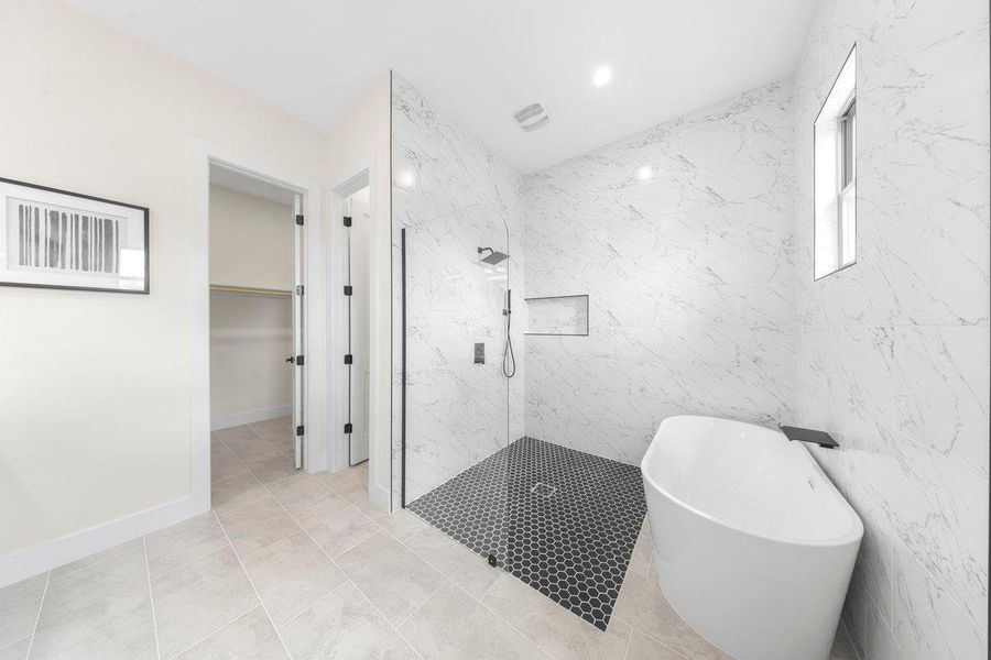 Bathroom with a freestanding tub, a walk in closet, a marble finish shower, tile walls, and light tile patterned floors Bathroom with a freestanding tub, a walk in closet, a marble finish shower, tile walls, and light tile patterned floors