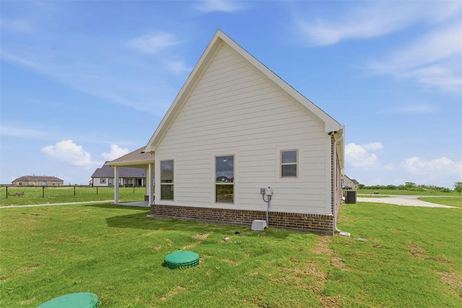 Side exterior of the property featuring white siding and a brick foundation