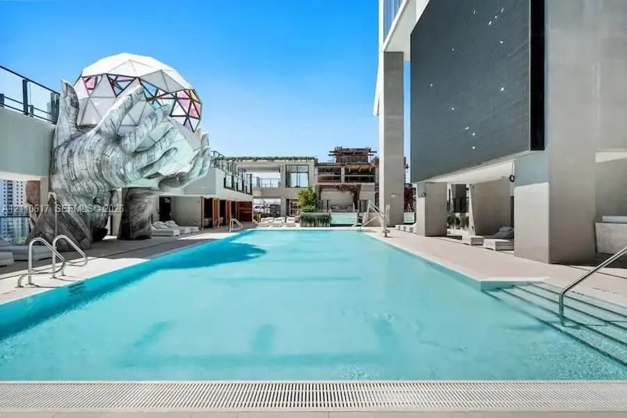 Rooftop swimming pool featuring a geometric dome sculpture, integrated stair entry, tiled surround, and structural pillars Rooftop swimming pool featuring a geometric dome sculpture, integrated stair entry, tiled surround, and structural pillars