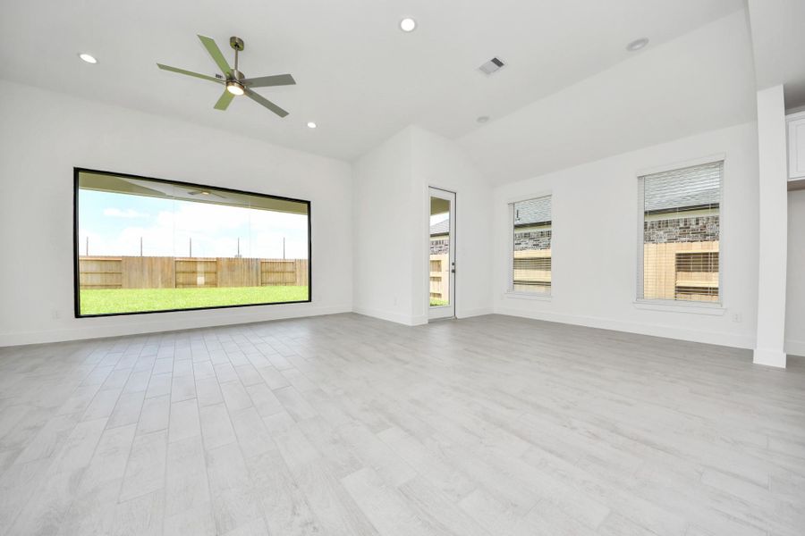 Welcome family and guests to your charming living room! With its high ceilings, recessed lighting, ceiling fan, custom paint, beautiful flooring, and large windows that let in abundant natural light, this room is perfect for gatherings.