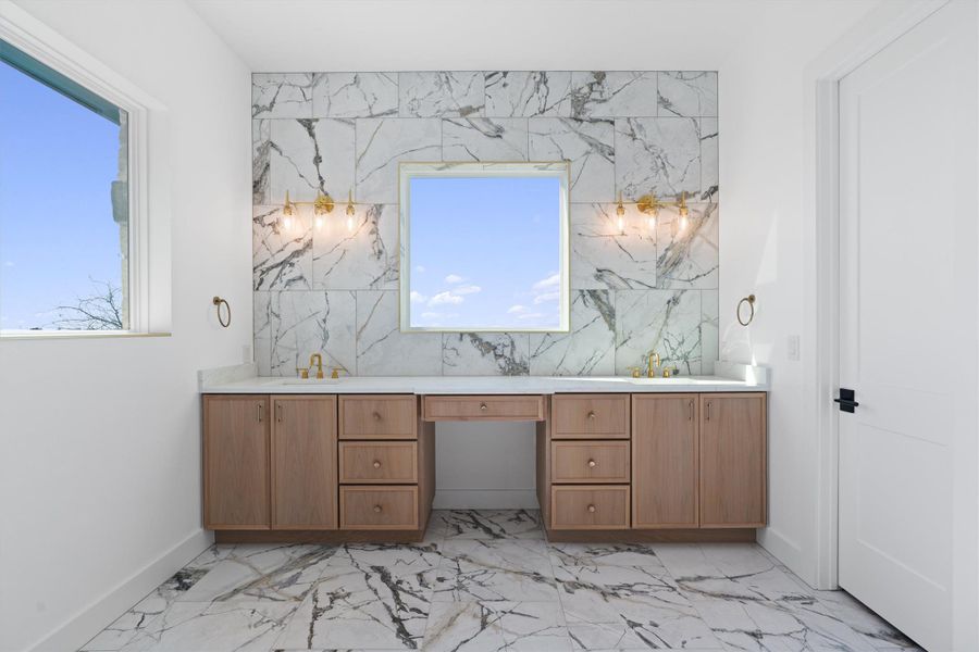 A striking tile backsplash accents this double vanity with ample storage and a makeup area. A striking tile backsplash accents this double vanity with ample storage and a makeup area.