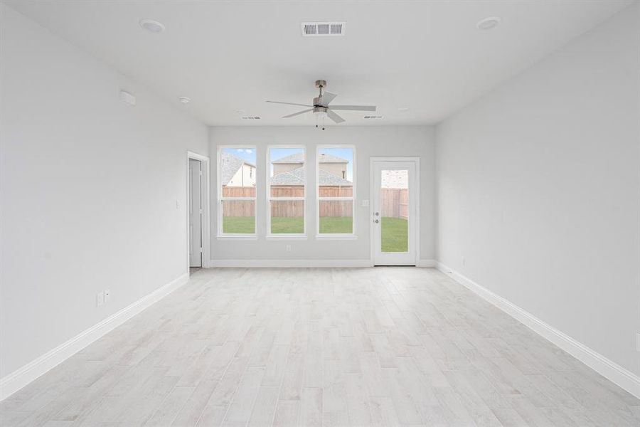 Empty room featuring a ceiling fan, visible vents, light wood-style flooring, and baseboards