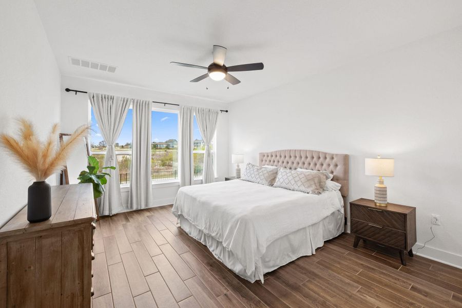 Bedroom with tiled flooring, ceiling fan and large windows.