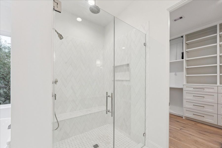 Framed glass shower with mosaic floor, Dolomite tile along the shower wall, and Afyon honed marble bench create a cohesive space.