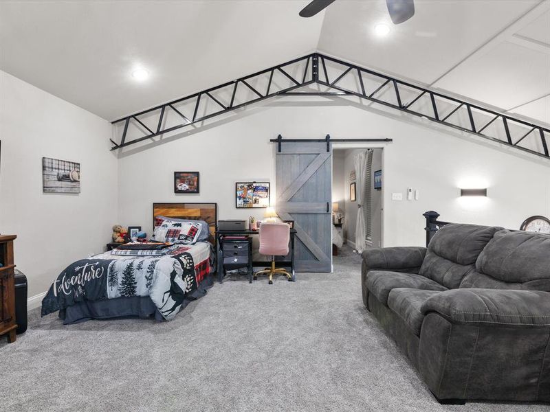 Carpeted bedroom featuring recessed lighting, a barn door, ceiling fan, and vaulted ceiling