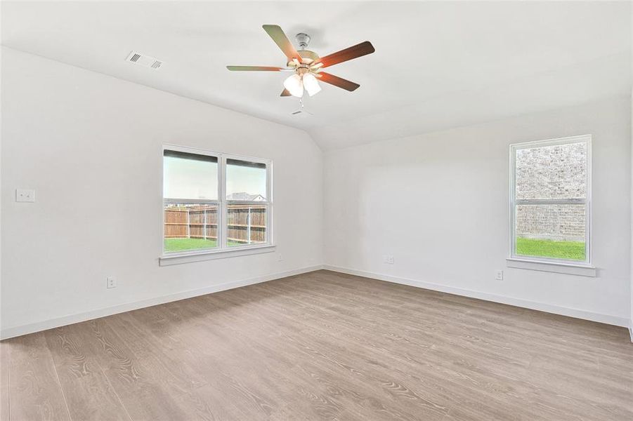 Spare room featuring light hardwood / wood-style flooring, lofted ceiling, ceiling fan, and a wealth of natural light