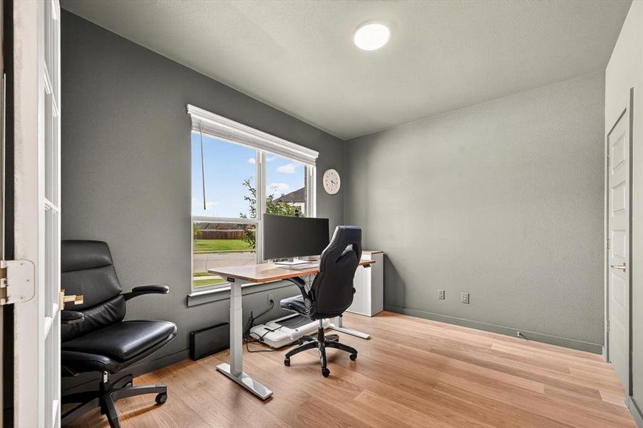 Room featuring light wood-finish flooring, a large window with white blinds, and recessed ceiling lighting
