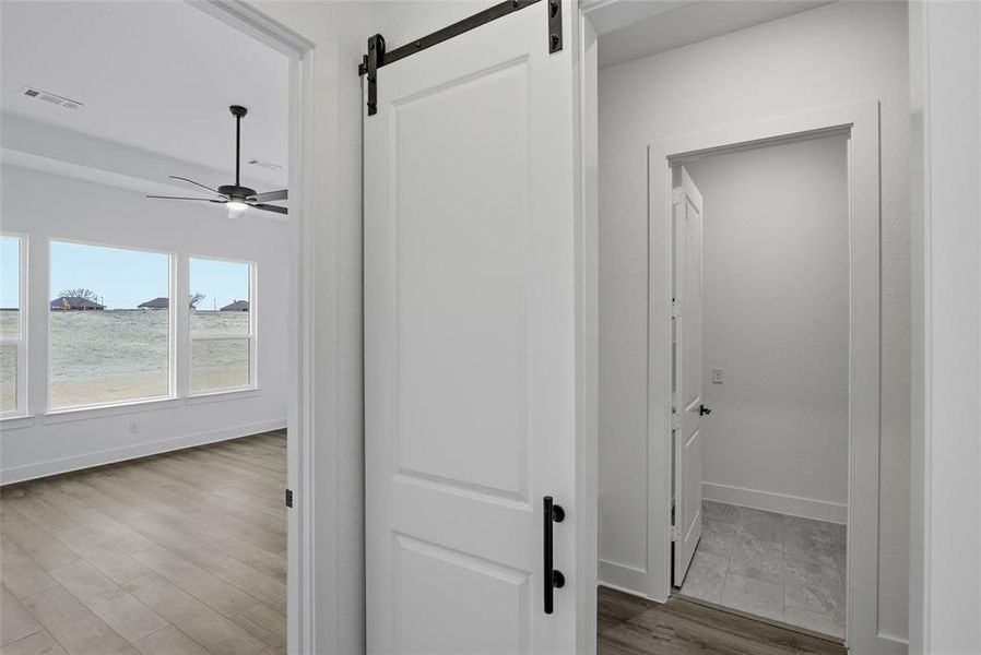 Hallway with a barn door and light wood-style flooring