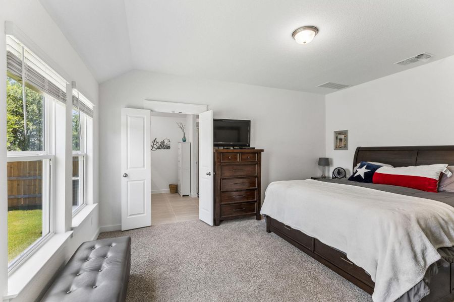Carpeted bedroom with vaulted ceiling and a flush-mount ceiling light fixture