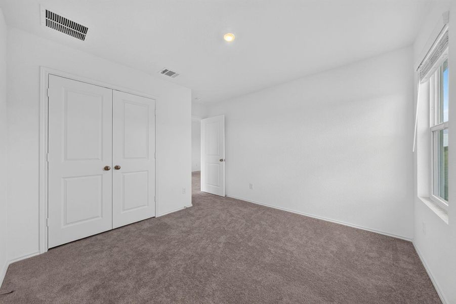 A well-lit bedroom features plush carpeting and a convenient reach-in closet. A well-lit bedroom features plush carpeting and a convenient reach-in closet.