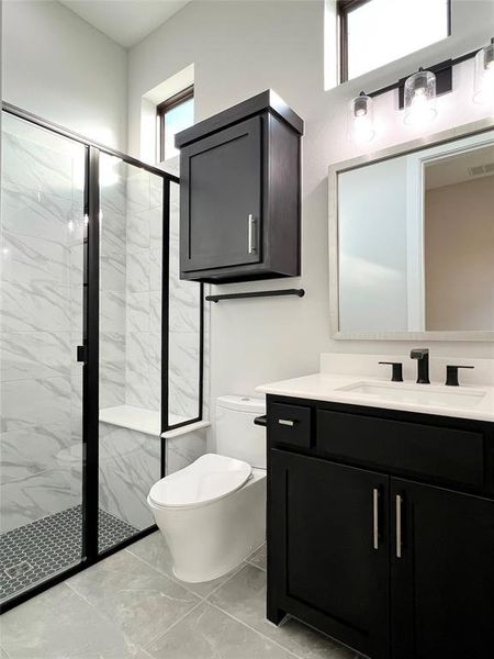 Bathroom with an enclosed shower, vanity, and toilet