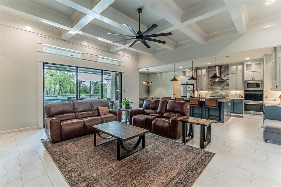 Living area with a ceiling fan, ornamental molding, coffered ceiling, recessed lighting, and light marble finish flooring Living area with a ceiling fan, ornamental molding, coffered ceiling, recessed lighting, and light marble finish flooring