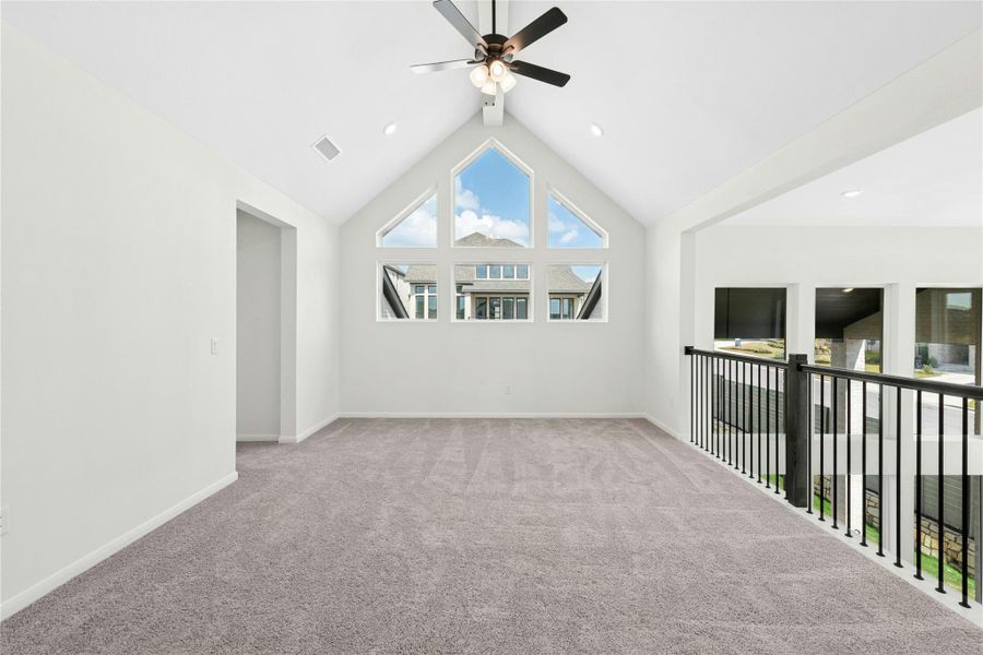 Empty room featuring carpet, ceiling fan, and high vaulted ceiling Empty room featuring carpet, ceiling fan, and high vaulted ceiling