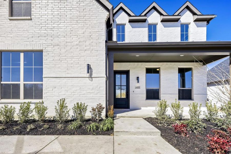 Entrance to property with a porch and brick siding