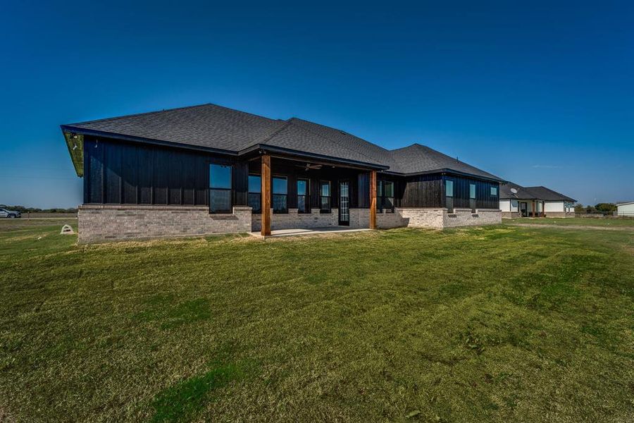 Back of house featuring ceiling fan, a lawn, and a patio area