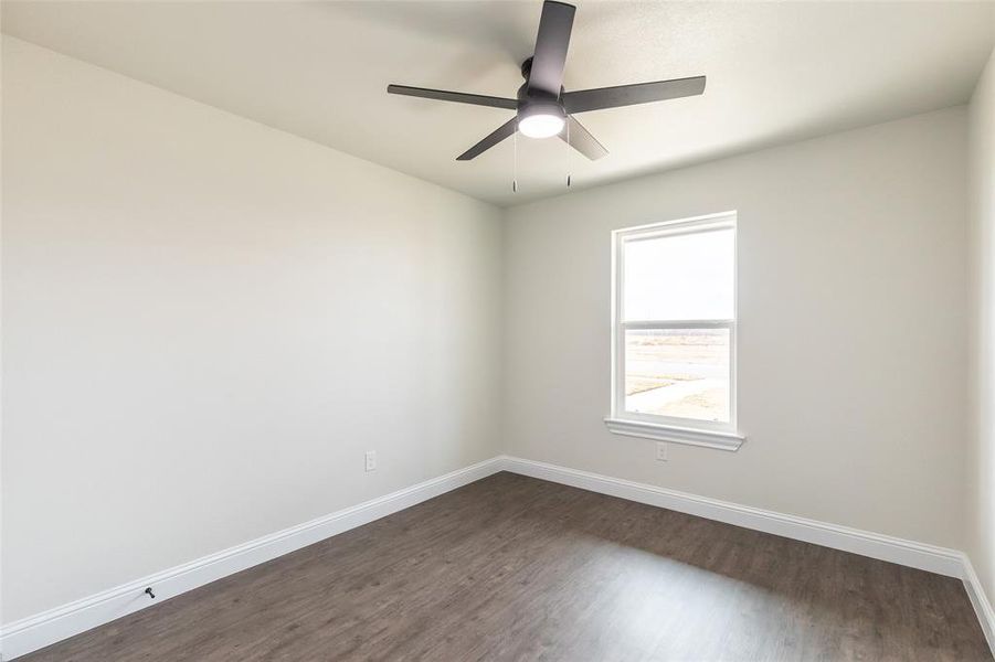 Room with light neutral wall paint, wood-finish flooring, white baseboards, and a contemporary ceiling fan with integrated lighting