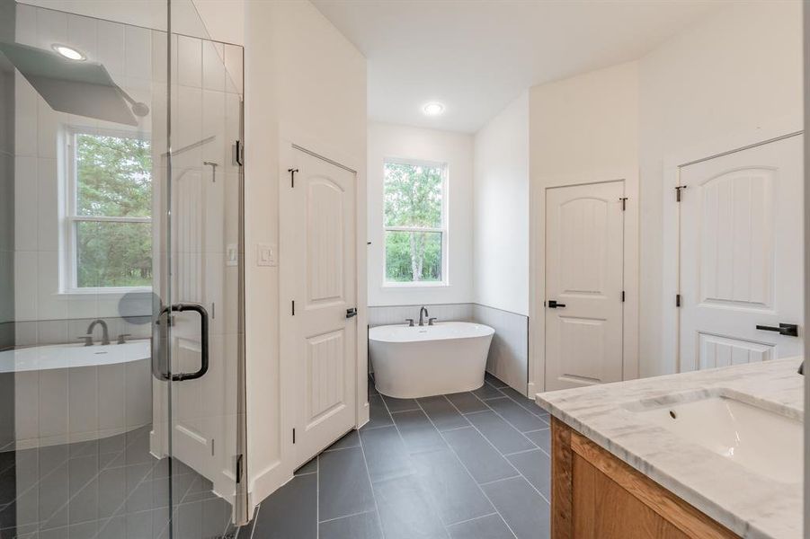 Bathroom featuring plenty of natural light, a soaking tub, vanity, and tile patterned flooring