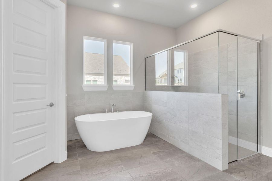 Full bathroom with recessed lighting, a freestanding bath, tile walls, and a stall shower Full bathroom with recessed lighting, a freestanding bath, tile walls, and a stall shower