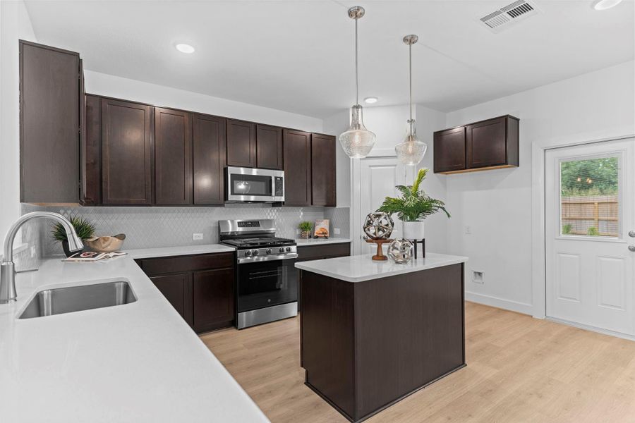 A second angle reveals the kitchen’s seamless connection to the dining and living areas, with contemporary finishes and a central island that anchors the heart of the home. **Image Representative of Plan Only and May Vary as Built**.