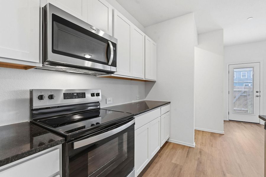 Kitchen area featuring stainless steel appliances, including an over-the-range microwave and electric range
