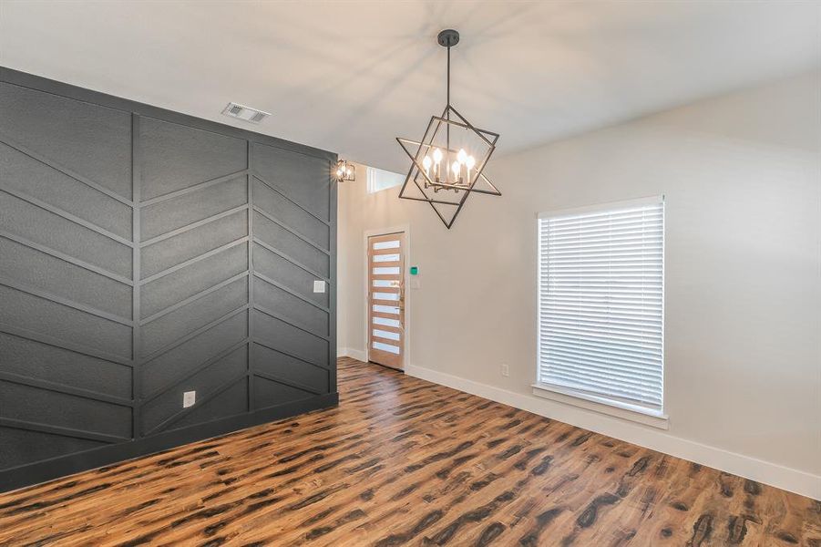 Spare room featuring an inviting chandelier and hardwood / wood-style flooring