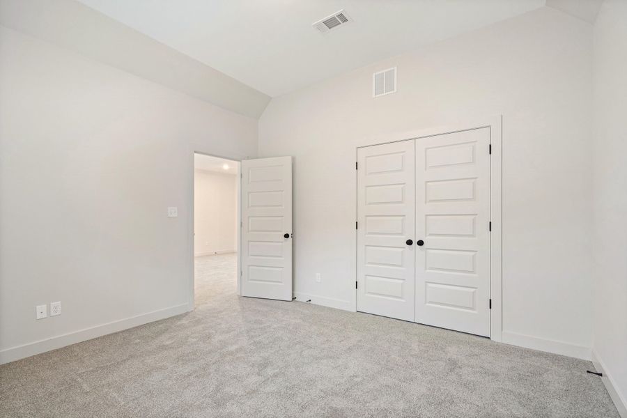 Neutral-toned room featuring a vaulted ceiling and light gray carpeting Neutral-toned room featuring a vaulted ceiling and light gray carpeting