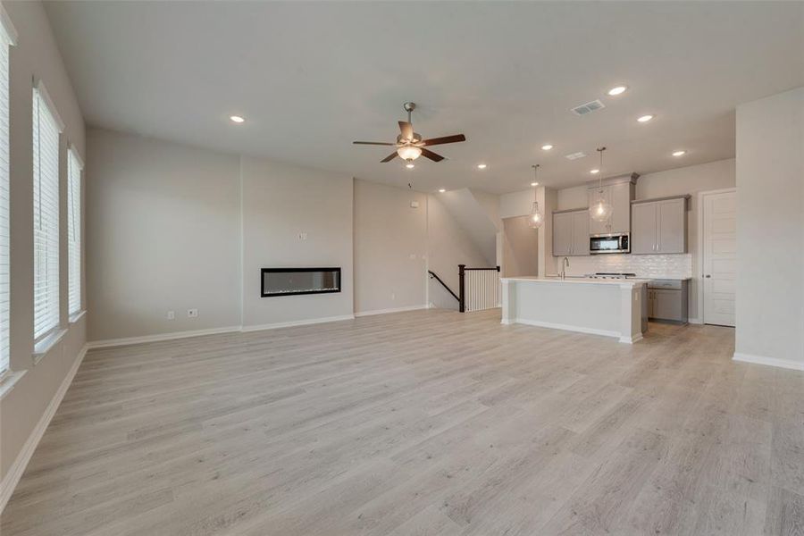 Unfurnished living room featuring sink, light wood-type flooring, and ceiling fan