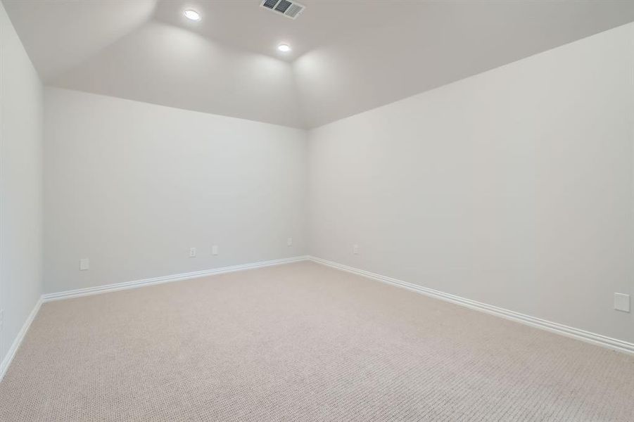 Carpeted empty room with vaulted ceiling