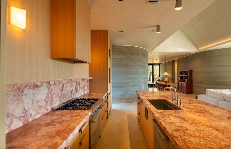 Kitchen with stainless steel appliances, light stone countertops, open floor plan, and modern cabinets