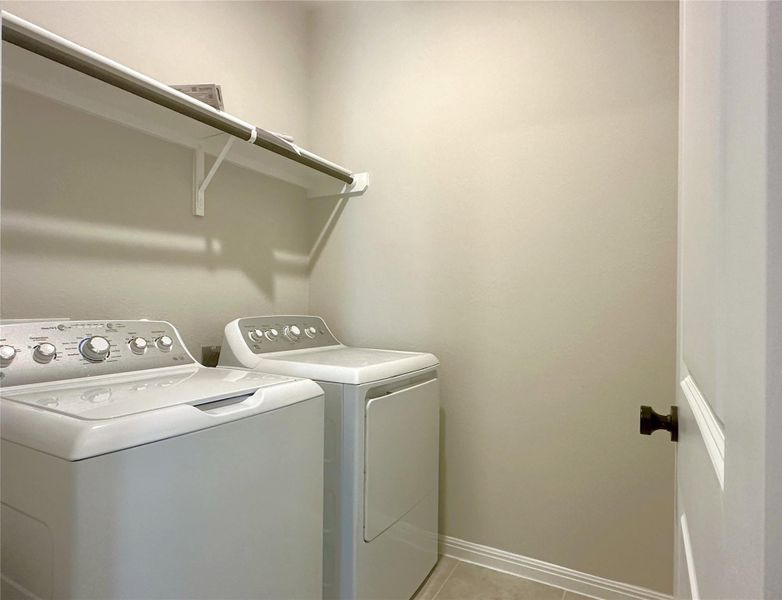Clothes washing area with washing machine and dryer, light tile floors, and baseboards Clothes washing area with washing machine and dryer, light tile floors, and baseboards