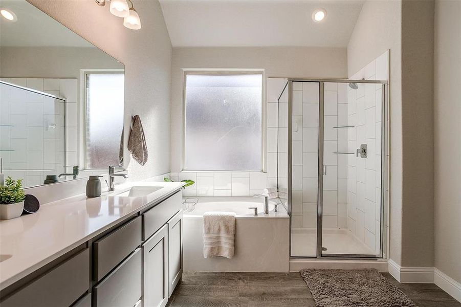 Primary bathroom with garden tub and walk-in shower with seating, dual sink vanity