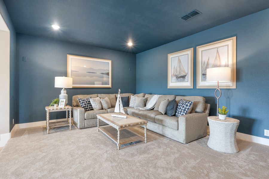 Living room with blue walls, gray sectional sofa, wood coffee table, and nautical wall art