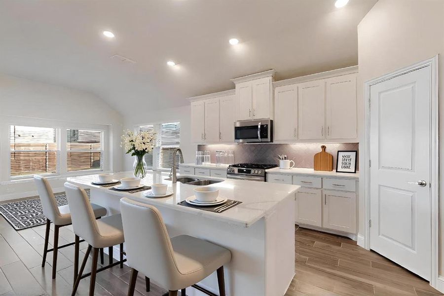 Kitchen featuring white cabinets, wood tiled floors, a kitchen breakfast bar, decorative backsplash, and appliances with stainless steel finishes
