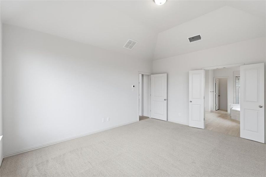 Unfurnished bedroom with light carpet and lofted ceiling