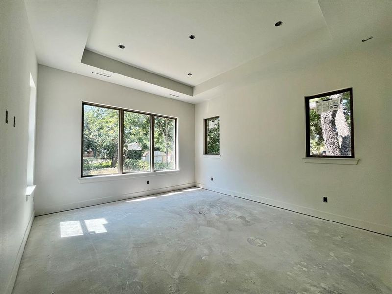 Unfurnished room with a tray ceiling and concrete flooring