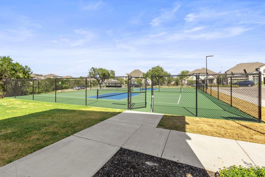 Concrete walkways lead directly to the enclosed community sport courts under clear skies.