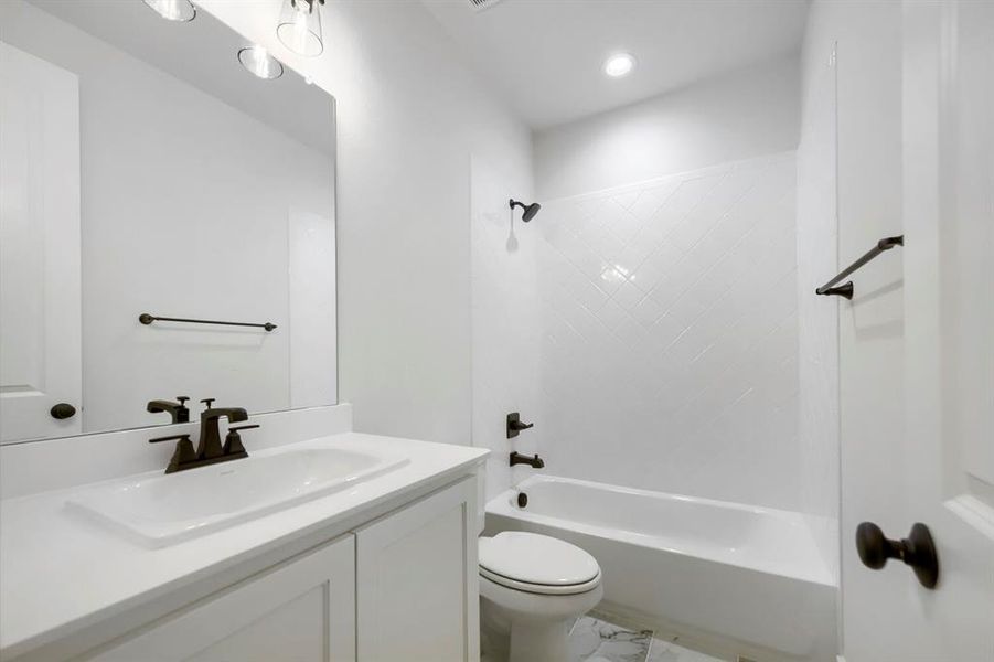 Bathroom with white vanity, integrated sink, bronze faucet, and large wall mirror Bathroom with white vanity, integrated sink, bronze faucet, and large wall mirror