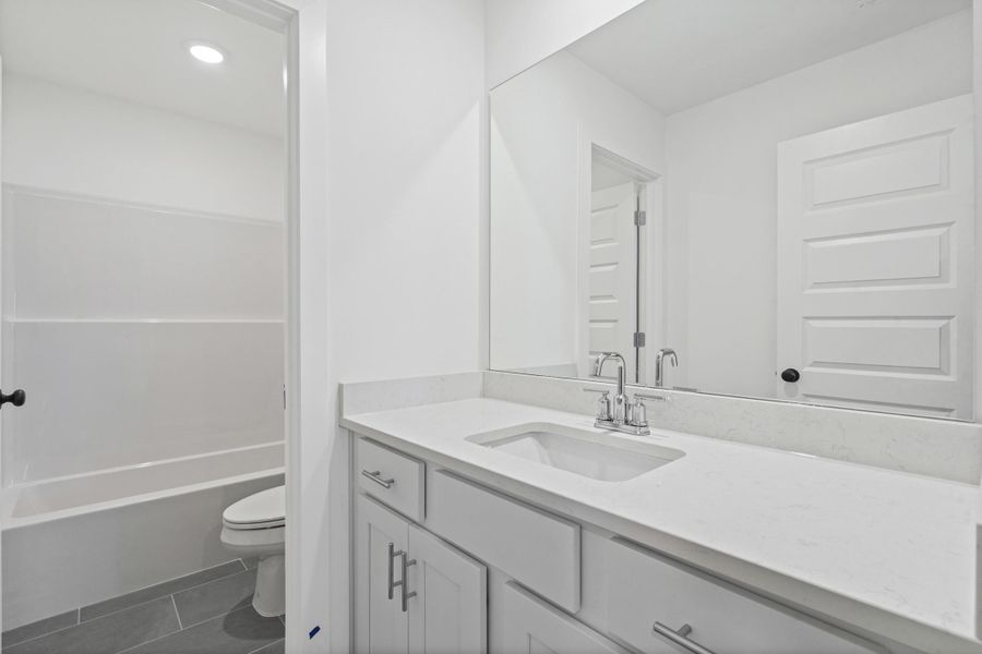 White vanity with a single basin sink, chrome faucet, and expansive countertop