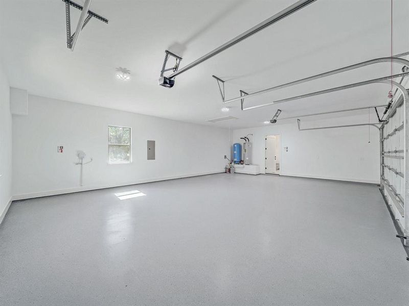 Garage featuring electric panel, a garage door opener, and water heater