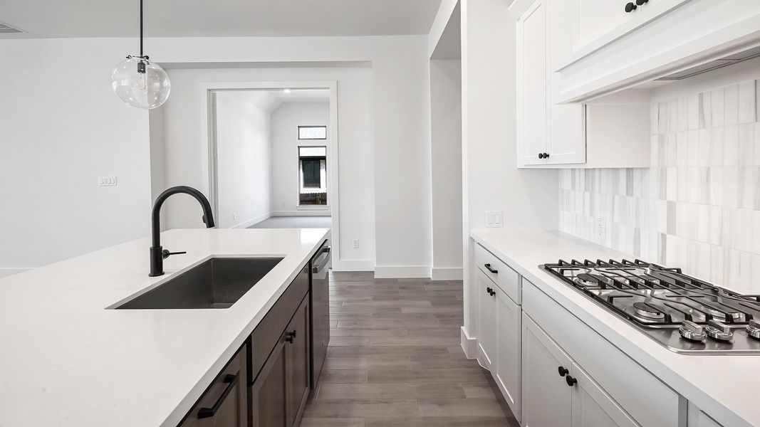 Kitchen with backsplash, appliances with stainless steel finishes, light countertops, and a sink