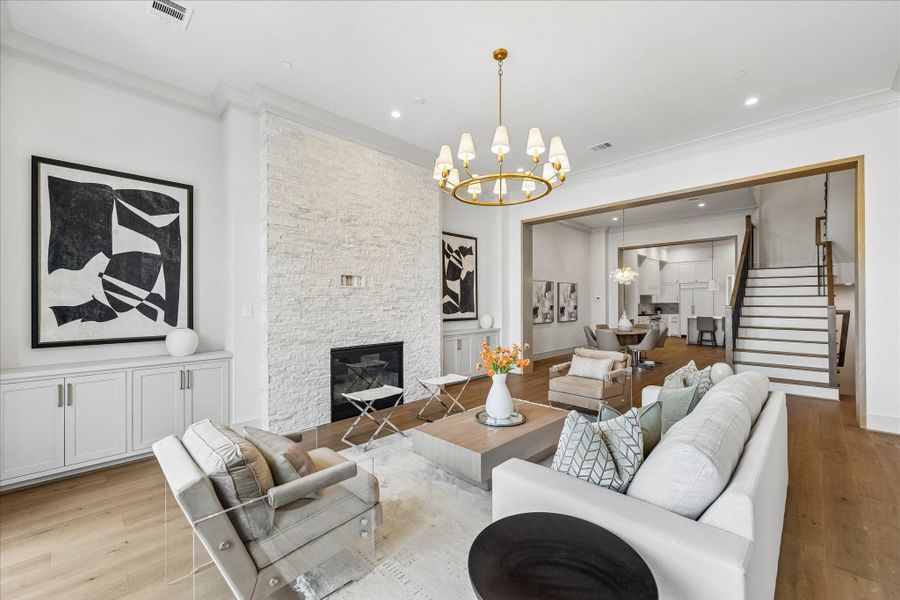 The lavish living room, complete with custom built-ins, stacked stone fireplace, and floor-to-ceiling windows. Twelve-foot ceilings, elegant crown moulding, and understated chandelier by Ziba create warmth and elegance.