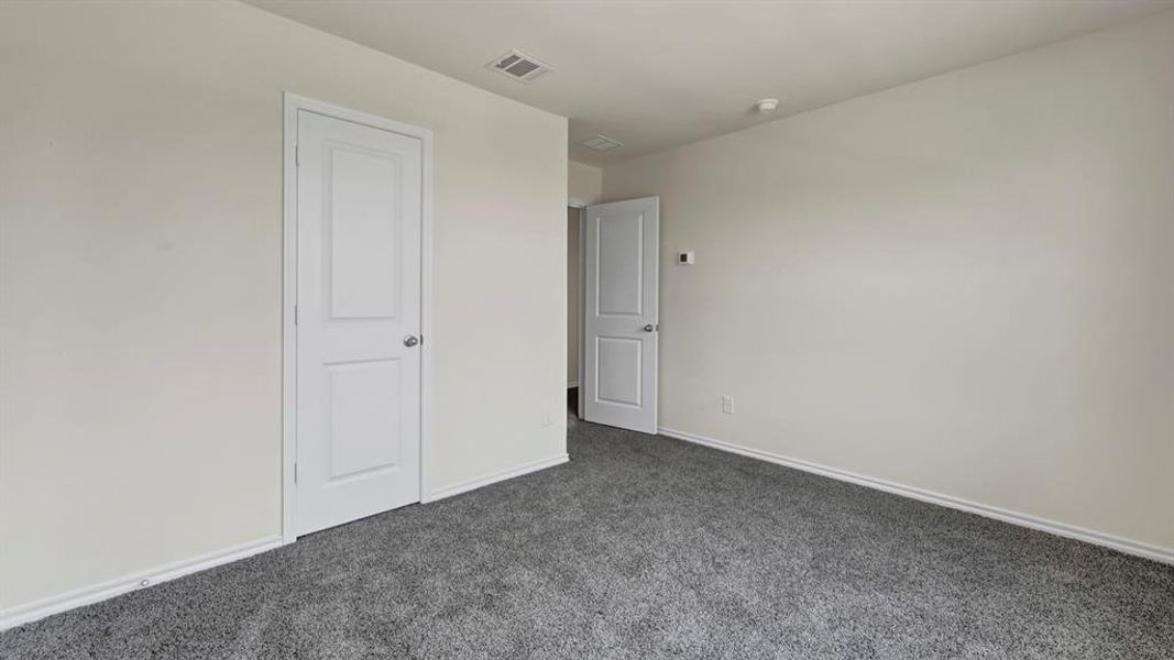 Spacious room featuring neutral wall tones, gray carpeting, and white trim