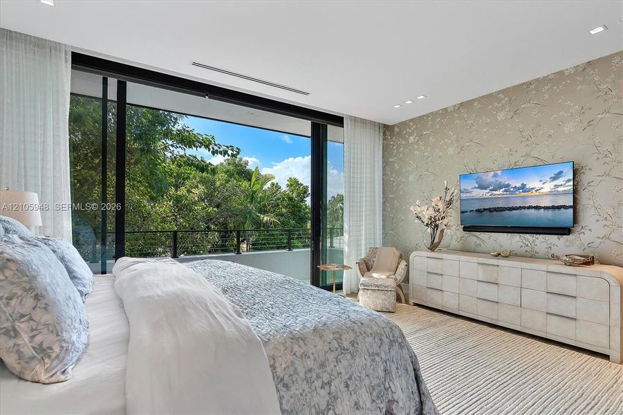 Floor-to-ceiling sliding glass doors, metal balcony railing, recessed ceiling lighting, and decorative wall covering