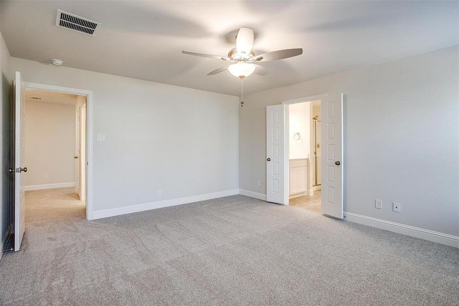 Unfurnished bedroom with visible vents, baseboards, ensuite bath, ceiling fan, and carpet